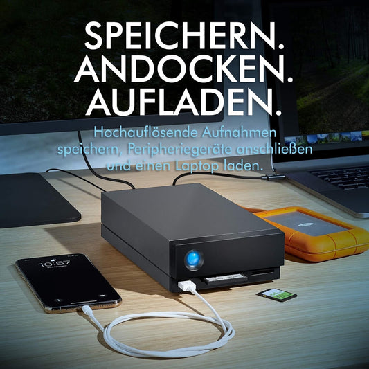 Eine schwarze LaCie 1big Dock Thunderbolt 3, 8TB externe Festplatte ist über ein weißes Kabel mit einem Smartphone auf einem Schreibtisch verbunden; ideal für Filmemacher, mit eingeblendetem deutschem Text zum Speichern, Andocken und Aufladen.