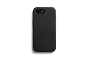 Eine Bellroy-Hülle – 0 Karten, iPhone 16e/17e – Schwarz umhüllt ein schwarzes Smartphone, das mit dem Display nach unten auf einem weißen Hintergrund liegt. Die strukturierte Hülle, die MagSafe-kompatibel ist und speziell für das iPhone 16e entwickelt wurde, trägt das Bellroy-Logo als Prägung im unteren Bereich.