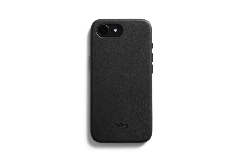 Eine Bellroy-Hülle – 0 Karten, iPhone 16e/17e – Schwarz umhüllt ein schwarzes Smartphone, das mit dem Display nach unten auf einem weißen Hintergrund liegt. Die strukturierte Hülle, die MagSafe-kompatibel ist und speziell für das iPhone 16e entwickelt wurde, trägt das Bellroy-Logo als Prägung im unteren Bereich.