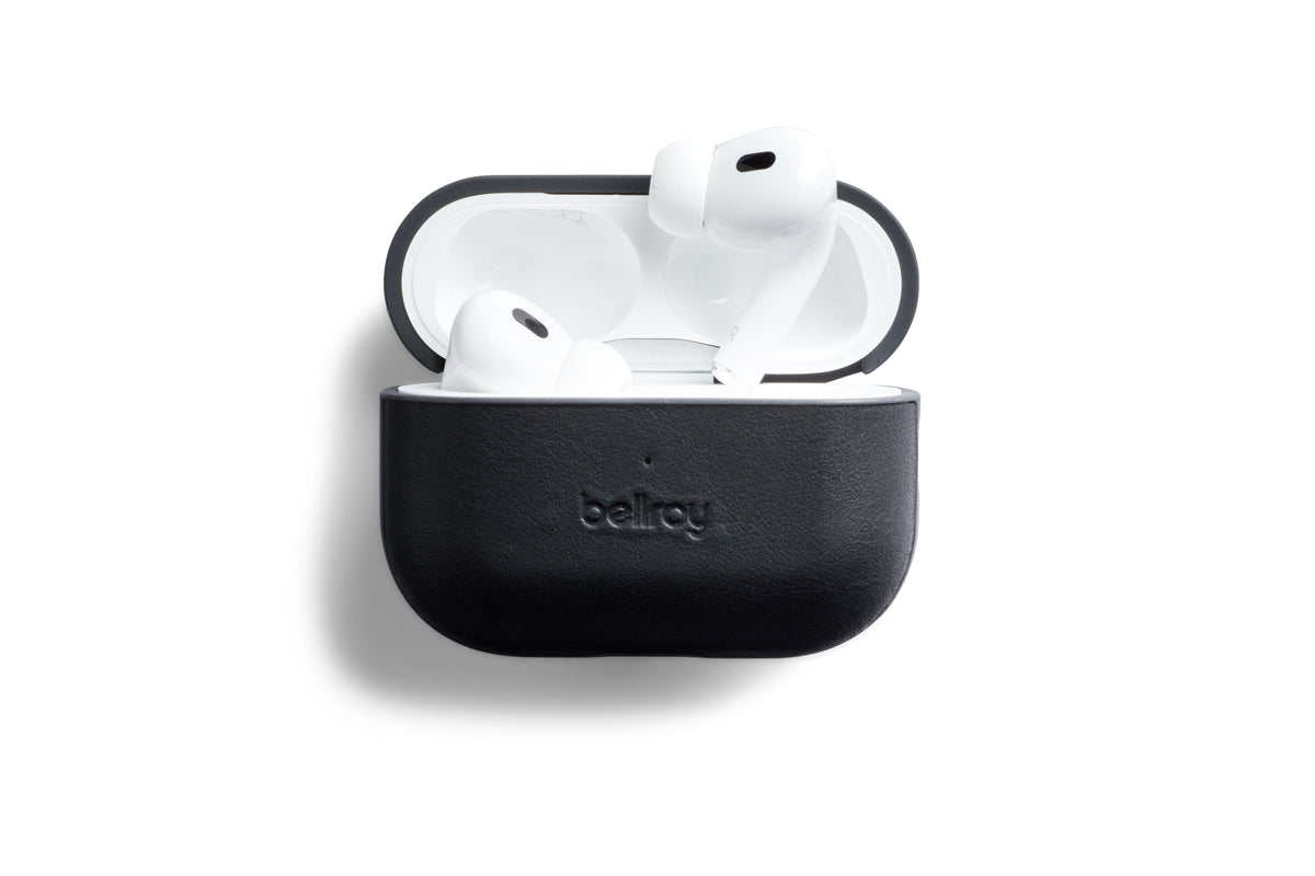 Ein Paar weiße kabellose Ohrhörer in einem offenen, schwarzen „Bellroy AirPods Jacket Pro“ (2. Generation)-Etui aus hochwertigem Leder, präsentiert vor einem weißen Hintergrund.