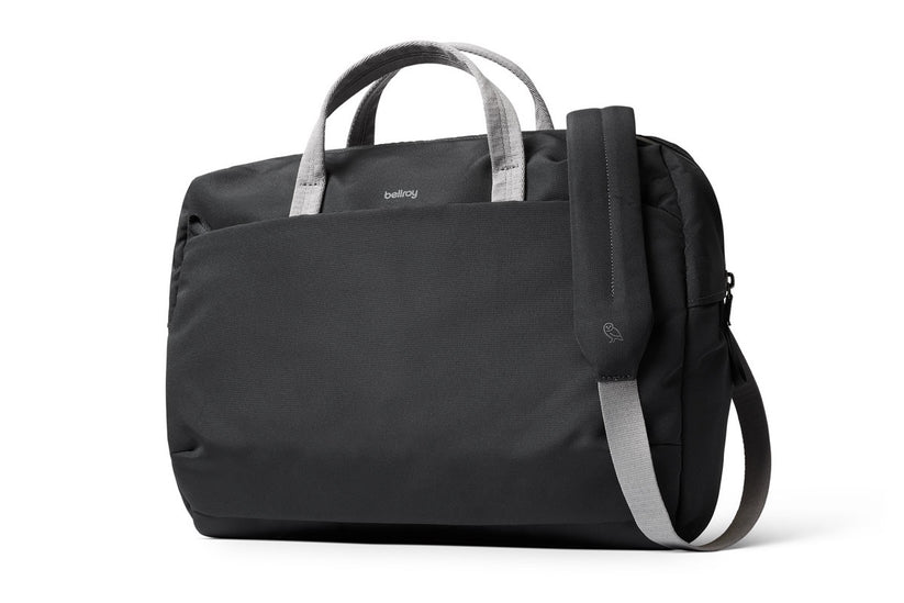 Wir stellen vor: die Bellroy Via Work Bag (Tech Briefcase) – Slate: Eine elegante schwarze Laptoptasche von Bellroy mit grauen Griffen und einem passenden, verstellbaren Schultergurt. Das minimalistische Design wird durch ein dezentes Bellroy-Logo oben in der Mitte abgerundet. Diese stilvolle Business-Tasche bietet ausreichend Platz für deinen Laptop und eignet sich ideal für den täglichen Gebrauch.