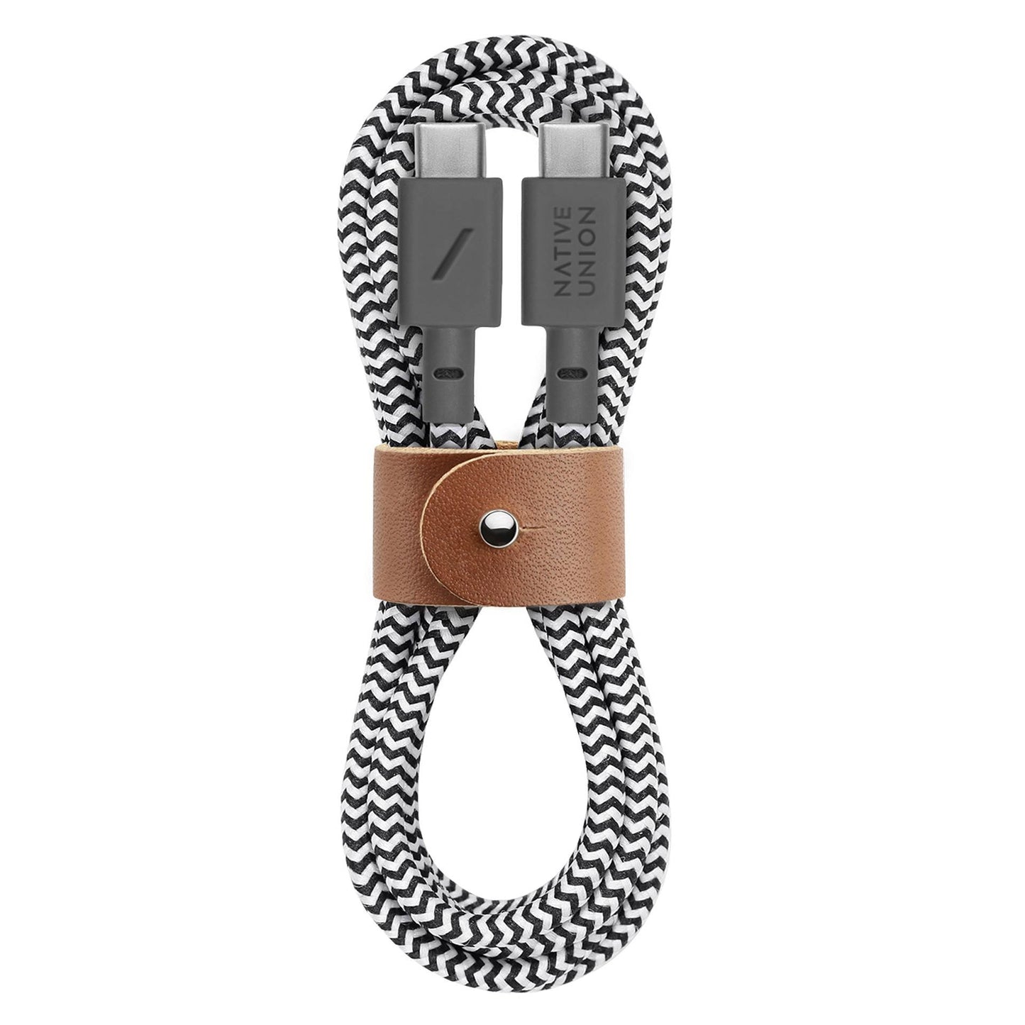 Das „Native Union Belt-Cable USB-C auf USB-C 1,2 m Zebra“ von Native Union ist ein spiralförmiges Ladekabel in Schwarz-Weiß mit Chevron-Muster und grauen Steckern, das mit einem braunen Lederriemen und einem Metall-Druckknopf sicher befestigt wird.