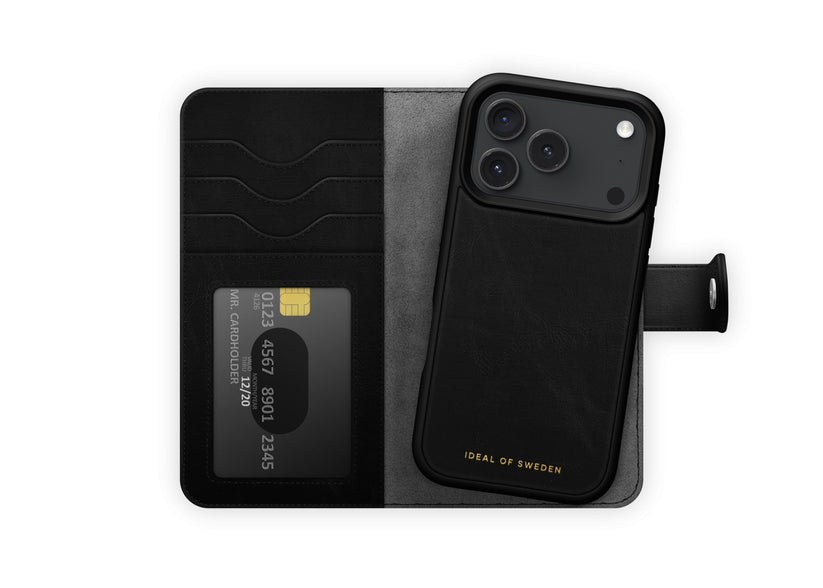 Eine schwarze „Ideal of Sweden“-Klapphülle mit MagSafe für das iPhone 17 Pro/18 Pro verfügt über Kartenfächer, von denen eines Platz für eine Kreditkarte bietet, und den Schriftzug „IDEAL OF SWEDEN“ in goldener Schrift auf dem Handyteil. Die Innenseite ist in Grau und Schwarz gehalten.