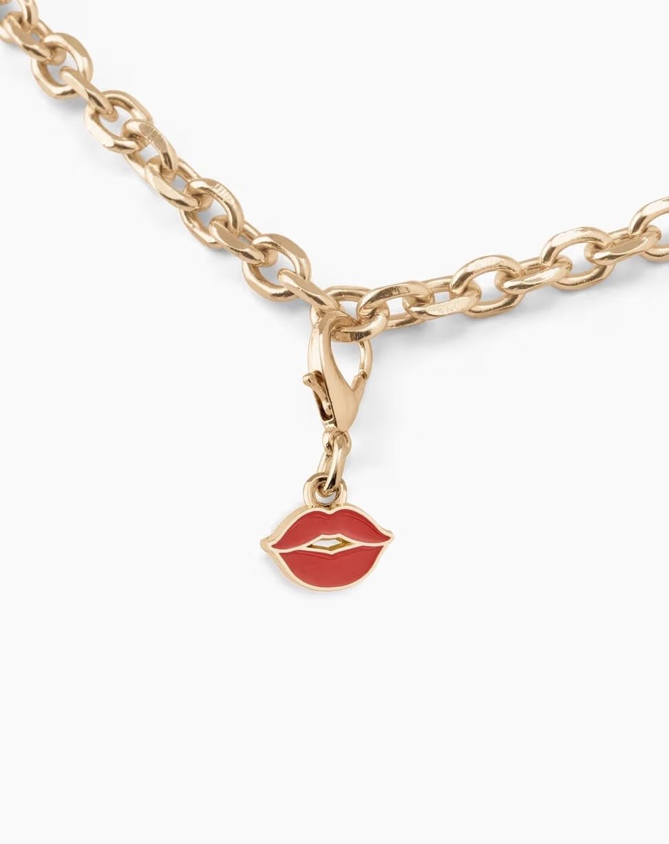 Eine Goldkette mit Karabinerverschluss ist mit dem „French Kiss“-Anhänger von Ideal of Sweden verziert, der die Form roter Lippen hat und an die stilvollen Accessoires von Ideal of Sweden erinnert.