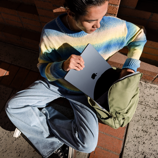 Vorderansicht einer Person, die ein zugeklapptes 15&quot MacBook Air in eine Tasche steckt