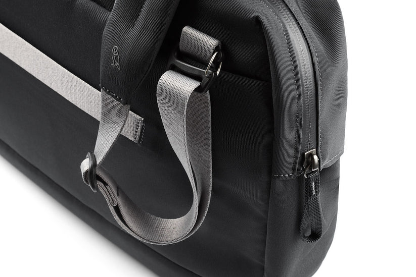 Nahaufnahme der Bellroy Via Work Bag (Tech Briefcase) in eleganter Schieferfarbe, mit strapazierfähigem schwarzem und grauem Stoff, einem bequemen Schultergurt mit dezentem Bellroy-Vogel-Logo und einem sicheren Reißverschluss. Diese stilvolle Business-Tasche von Bellroy vereint Funktionalität mit Eleganz und ist damit die perfekte wasserfeste Laptoptasche für Ihren täglichen Weg zur Arbeit.