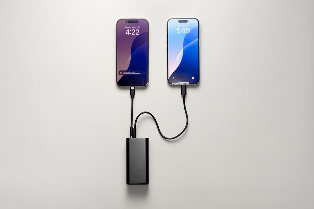 Mophie’nin zarif mophie Powerstation 10K - Schwarz modeline iki akıllı telefon bağlanmıştır; her ikisi de sade, açık gri bir yüzey üzerinde uyumlu siyah şarj kabloları kullanmaktadır. Her iki telefon da saat bilgisinin göründüğü farklı kilit ekranları sergilemekte ve bu, 10.000 mAh kapasiteli bu USB-C şarj cihazının güvenilir şarj performansını vurgulamaktadır.