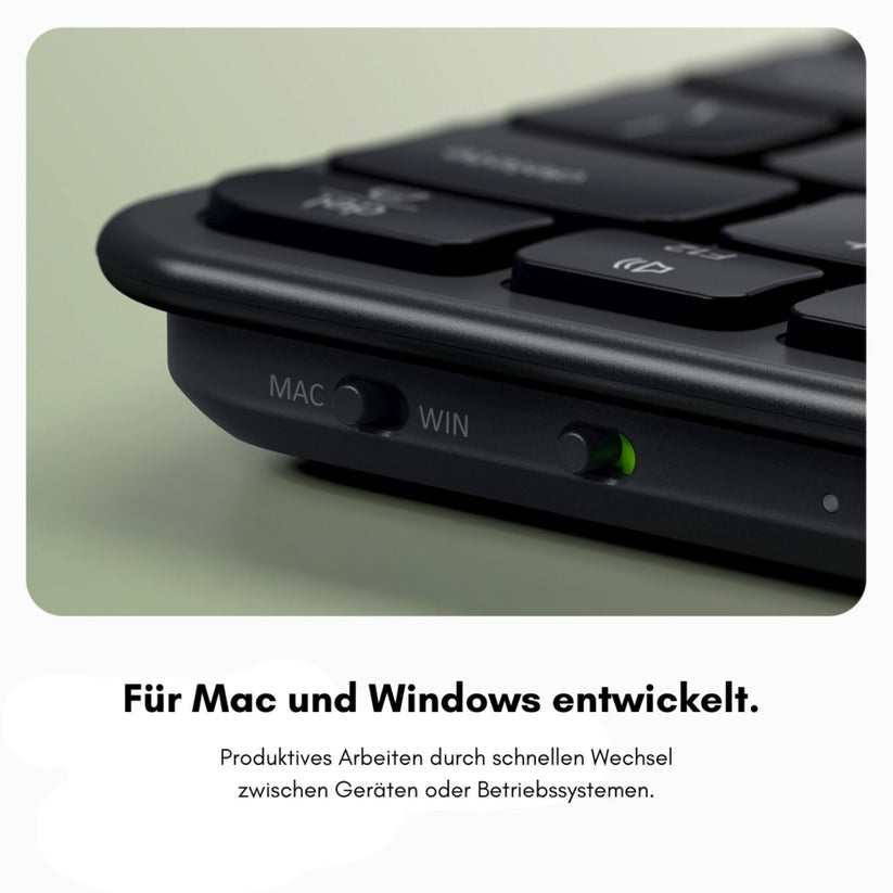 Nahaufnahme der Satechi Slim EX3 Wireless Keyboard Space Black DE mit Schaltern, die mit „MAC“ und „WIN“ beschriftet sind, sowie einer grünen Kontrollleuchte. Der darunter stehende deutsche Text hebt die kabellose Tastatur mit deutschem Tastaturlayout und ihre Kompatibilität mit Mac und Windows hervor, was einen schnellen Wechsel zwischen Geräten oder Systemen ermöglicht.