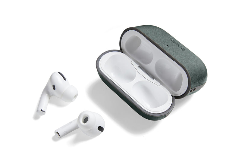 Zwei weiße kabellose Ohrhörer liegen neben einer geöffneten, leeren Bellroy AirPods Jacket Pro (2. Generation) – Everglade-Hülle mit weißem Innenfutter, alles vor einem schlichten weißen Hintergrund. Das maßgeschneiderte Bellroy-Etui besticht durch hochwertiges Design und sorgt mit USB-C-Aufladung für komfortables und schnelles Aufladen Ihrer Ohrhörer.