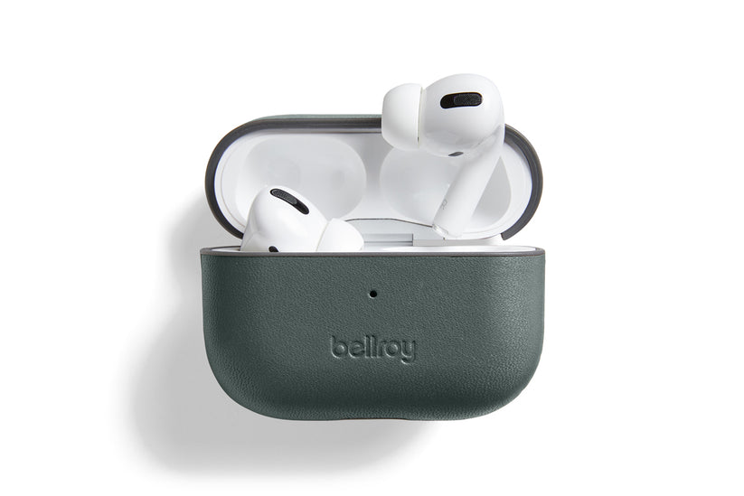 Ein Paar weiße kabellose Ohrhörer in einer offenen, dunkelgrünen „Bellroy AirPods Jacket Pro (2. Generation) – Everglade“-Hülle aus hochwertigem Leder, präsentiert vor weißem Hintergrund, um die passgenaue Form und die praktische USB-C-Ladefunktion zu verdeutlichen.