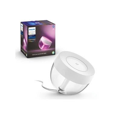Die Philips Hue Iris Tischleuchte, weiß von Philips wird eingesteckt mit ihrer Verpackung und einem lilafarbenen Lichteffekt gezeigt und präsentiert ihr weißes, rundes Design und die praktische App-Steuerung.
