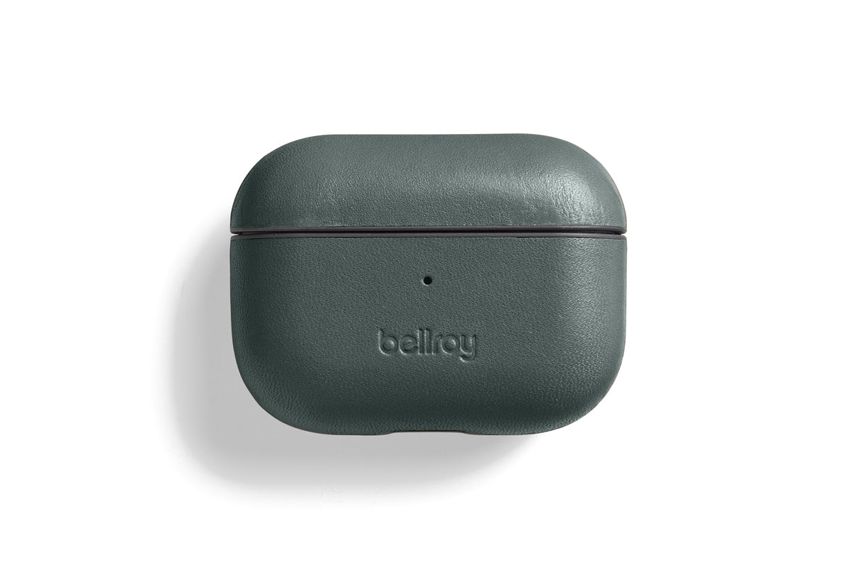 Eine Bellroy AirPods Jacket Pro (2. Generation) – Everglade aus dunkelgrünem Premium-Leder ist geschlossen auf einem weißen Hintergrund abgebildet. Auf der Vorderseite ist das geprägte Bellroy-Logo zu sehen, über dem sich eine kleine Kontrollleuchte befindet. Diese maßgeschneiderte Hülle bietet modernen Komfort mit USB-C-Aufladung.