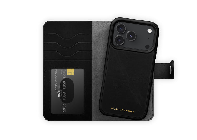 Eine schwarze Klapphülle von Ideal of Sweden mit MagSafe für das iPhone 17 Pro Max/18 Pro Max bietet Platz für ein Smartphone sowie drei Karten, darunter eine Kreditkarte. Am unteren Rand steht in goldenen Buchstaben „IDEAL OF SWEDEN“, was das skandinavische Design in puncto Eleganz und Funktionalität unterstreicht.