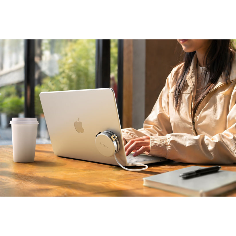 Bir kişi, yeniden kullanılabilir bir kahve bardağı, defter ve kalemle birlikte ahşap bir masada MacBook'unda yazı yazarken, pencerenin dışındaki yeşillik manzarasını seyrediyor. Dizüstü bilgisayarın yanında, geri çekilebilir bir şerit metre ve Satechi tarafından üretilen, birden fazla cihaza pratik bağlantı imkanı sunan Satechi OntheGo 5′i-1′de Çoklu Bağlantı Noktalı Adaptör (Gümüş) bulunuyor.
