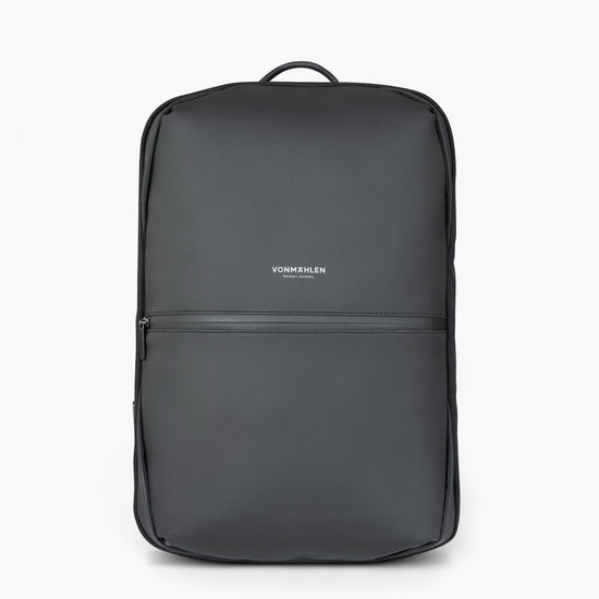 The Vonmählen Tech Bag Horizon is a sleek, minimalist black rucksack with a front zipper pocket, water-repellent material, smooth texture, top handle, subtle Vonmählen logo in white, and a USB-C port for convenient charging on the go.