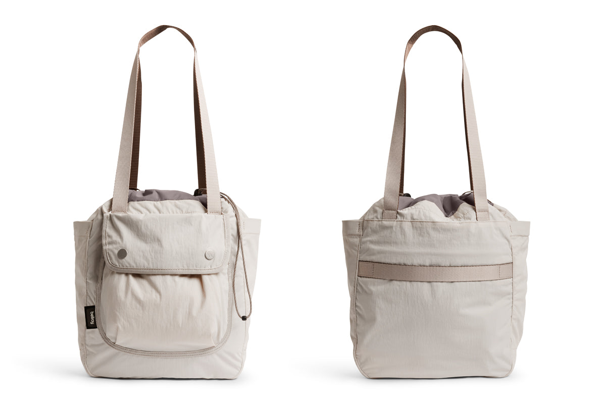 Zwei Bellroy Cinch Tote-Taschen in der Farbe „Oat“ sind nebeneinander abgebildet, wobei sowohl die Vorderseite (mit einer Tasche mit Knopfverschluss) als auch die Rückseite (mit einer horizontalen Tasche) der Tasche zu sehen sind. Beide verfügen über lange Henkel, einen Kordelzugverschluss am oberen Rand und bieten reichlich Platz für Ihre wichtigsten Dinge – damit sind sie ideale große Taschen für den täglichen Gebrauch.