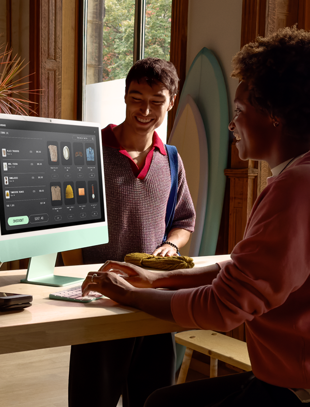 Two people in a well-lit room looking at products on the iMac display with nanotexture glass