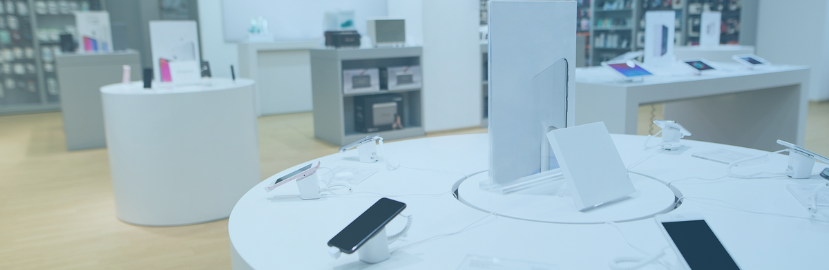 Ein modernes Elektronikgeschäft mit Smartphones und Tablets, die auf runden weißen Tischen ausgestellt sind, umgeben von Regalen und Theken, auf denen verschiedene technische Produkte in einer sauberen, hellen Umgebung präsentiert werden.